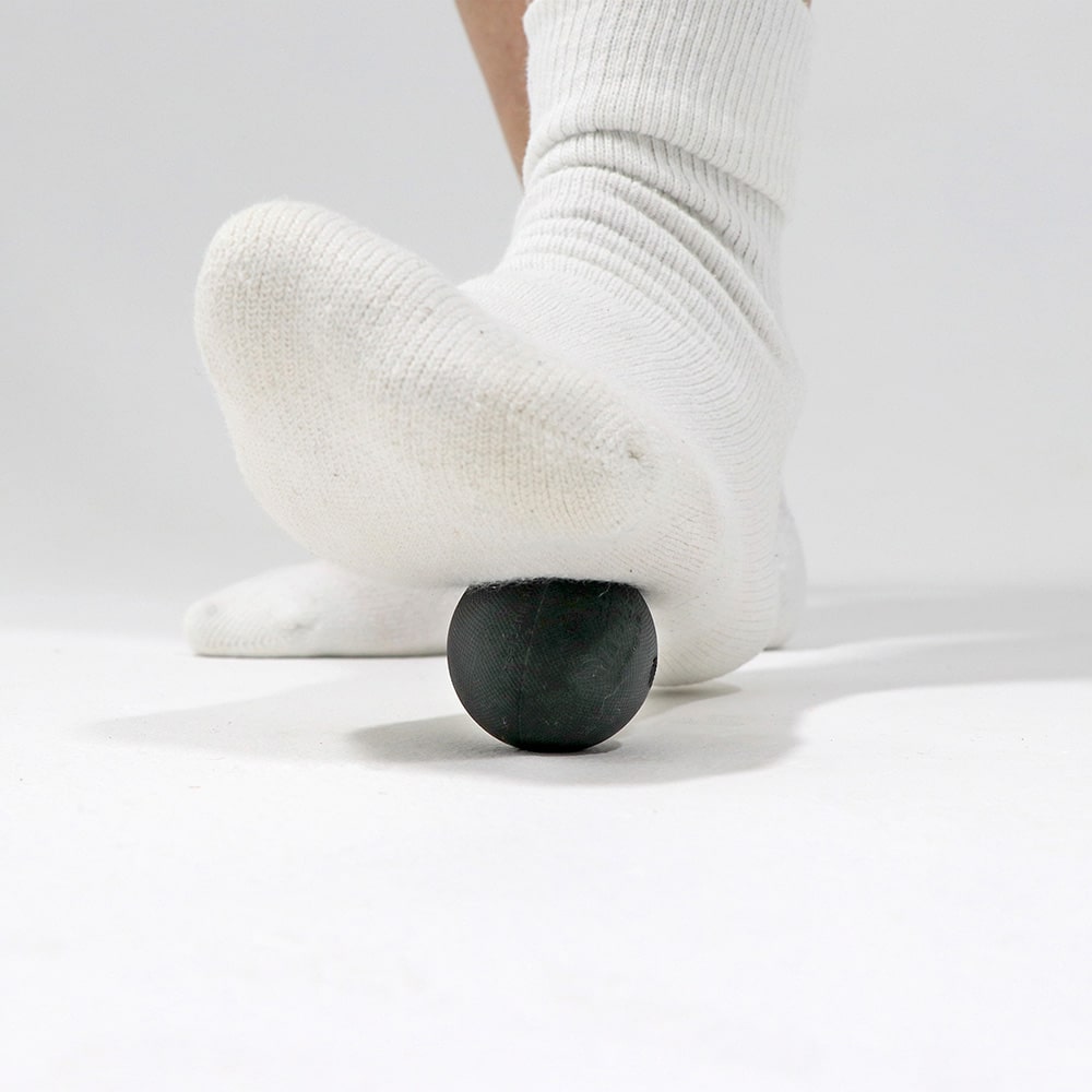 Tiger Ball 1.7 positioned under heel performing targeted trigger point release with steady pressure to relieve heel pain and plantar fasciitis tension.